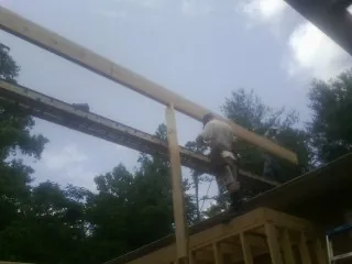 Carpenter setting a ridge beam over a new addition frame in Buffalo